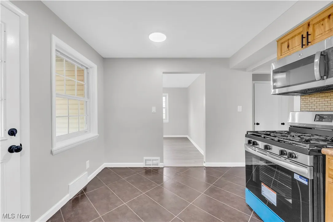 Kitchen with stainless steel appliances, dark tile patterned flooring, and decorative backsplash