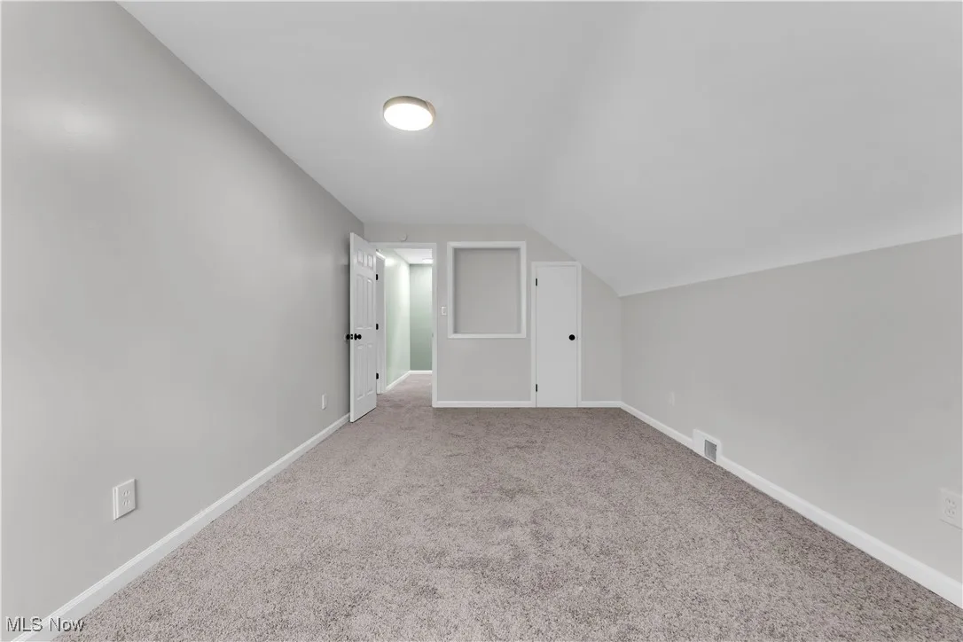 Additional living space with light carpet and lofted ceiling