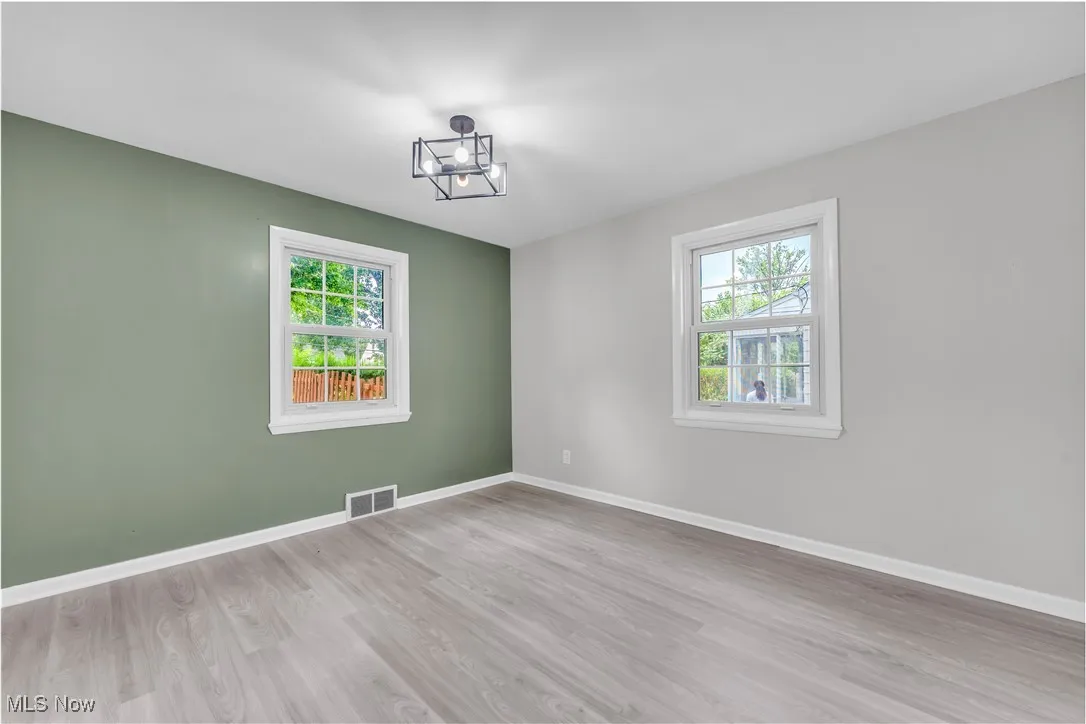 Spare room with light wood-type flooring and a chandelier