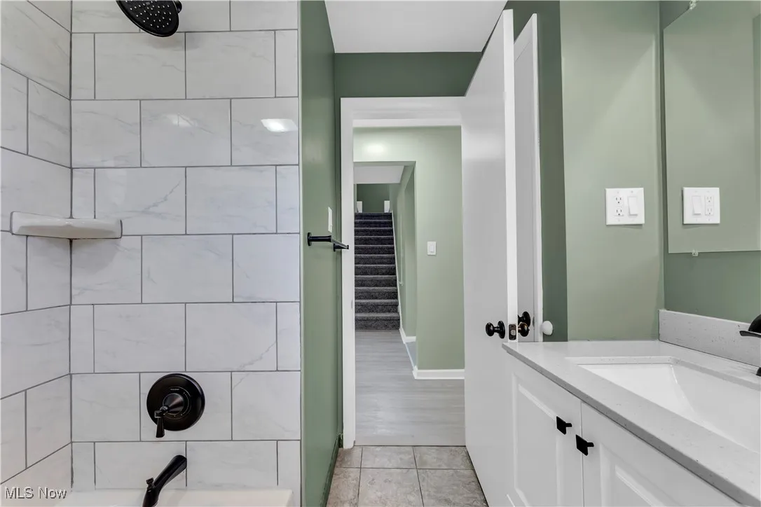 Bathroom featuring vanity,  shower combination, and light tile patterned floors