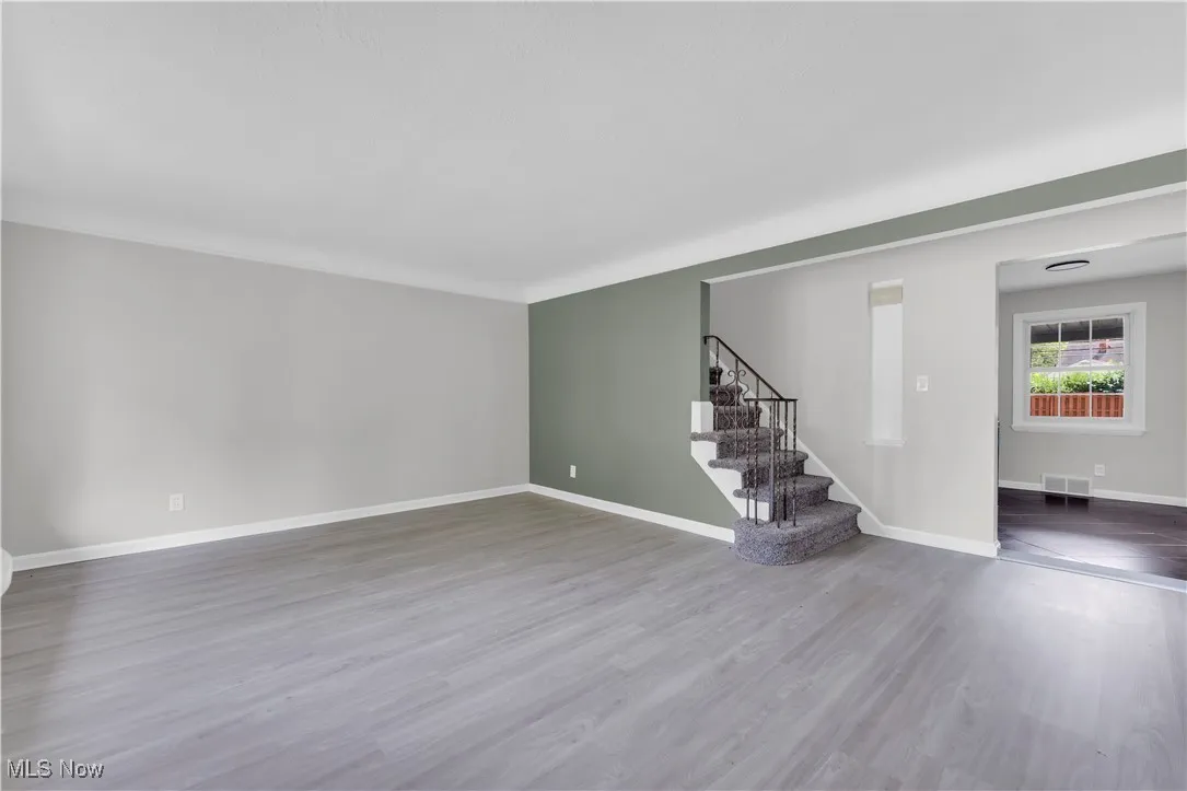 Unfurnished living room featuring wood finished floors and stairway
