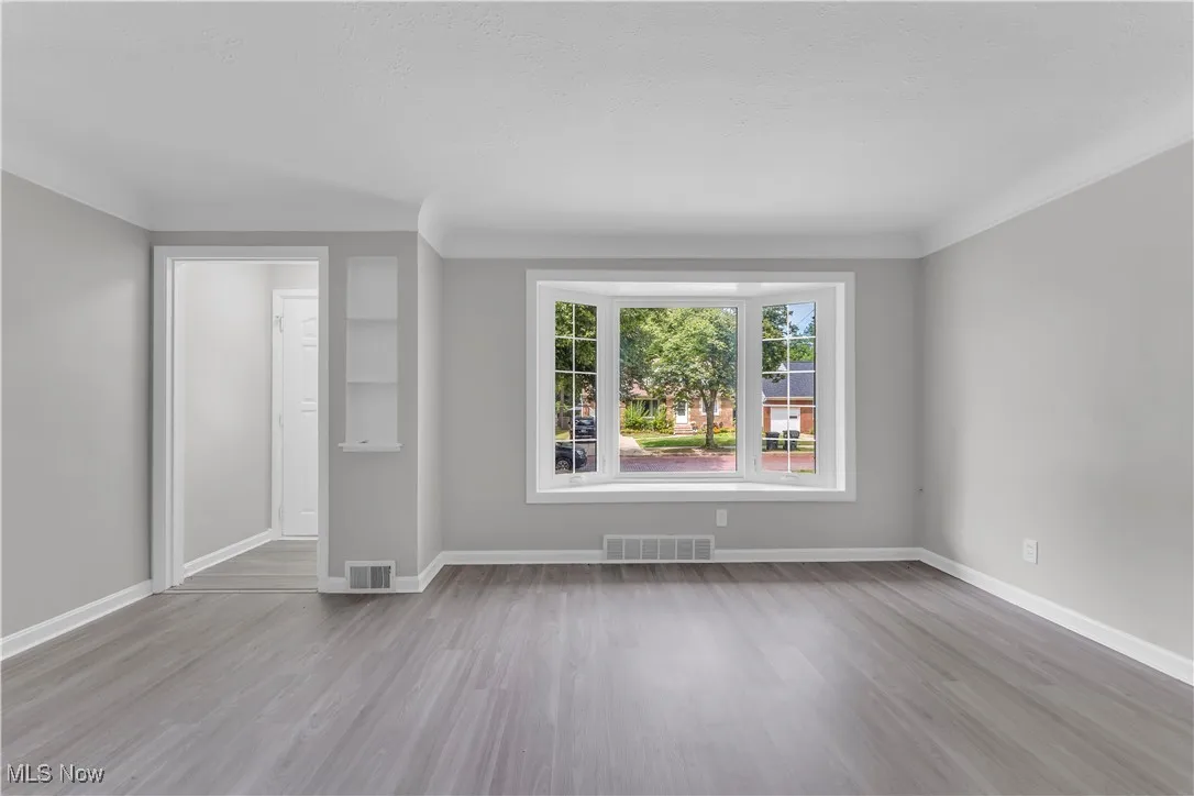 Empty room featuring light wood-style floors and ornamental molding