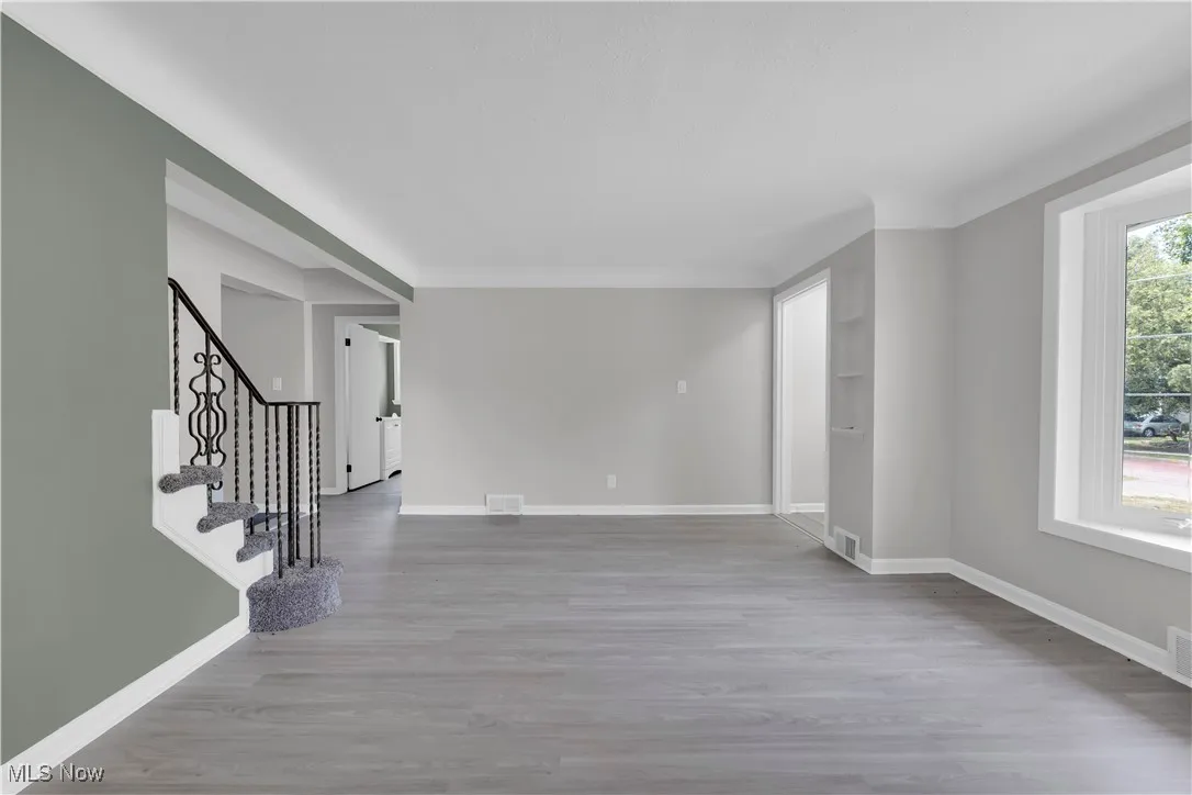 Spare room with light wood-style flooring and stairway