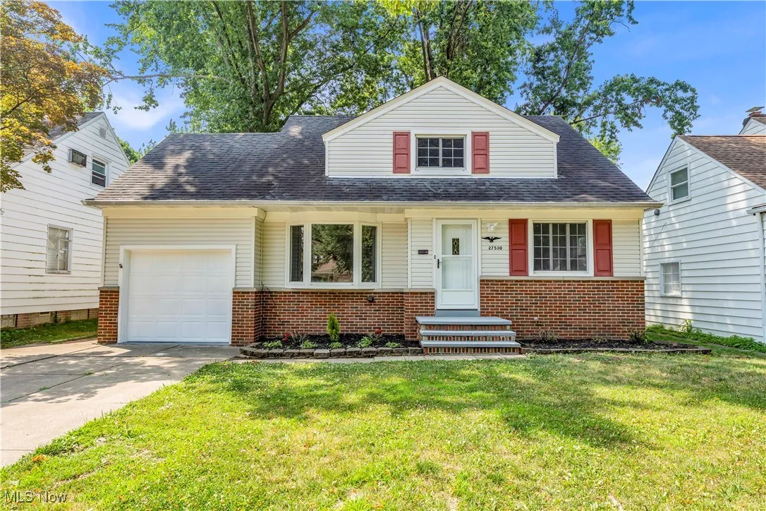 View of front facade with concrete driveway, brick siding, a front lawn, and a garage