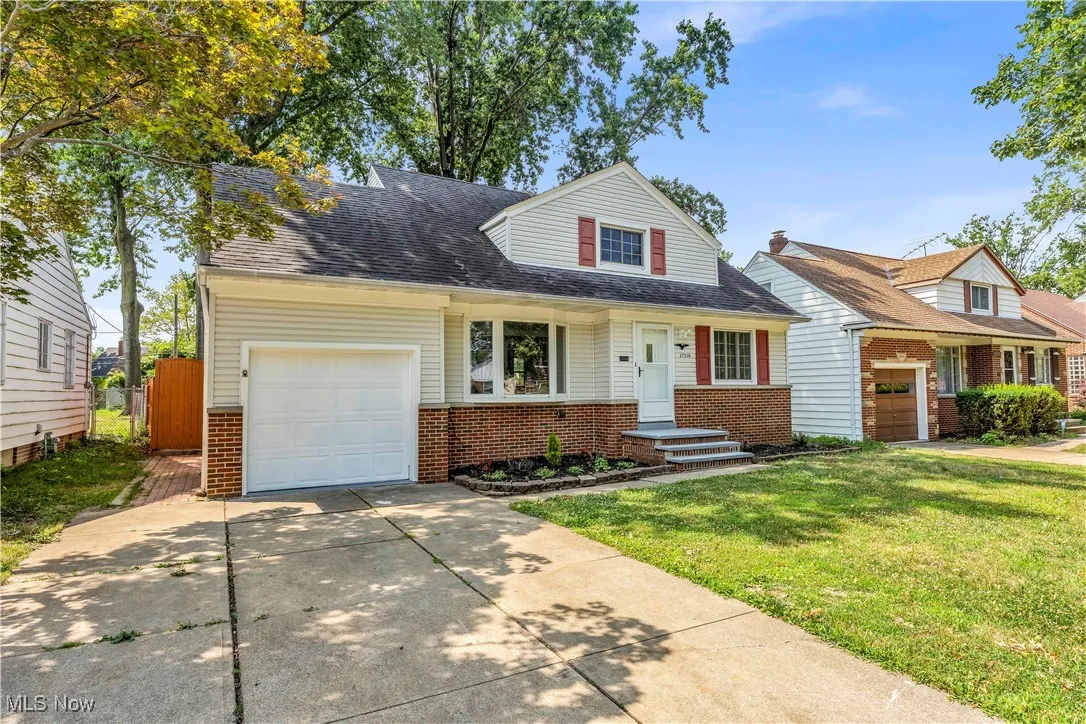 View of front of home featuring driveway, a gate, brick siding, a garage, and roof with shingles