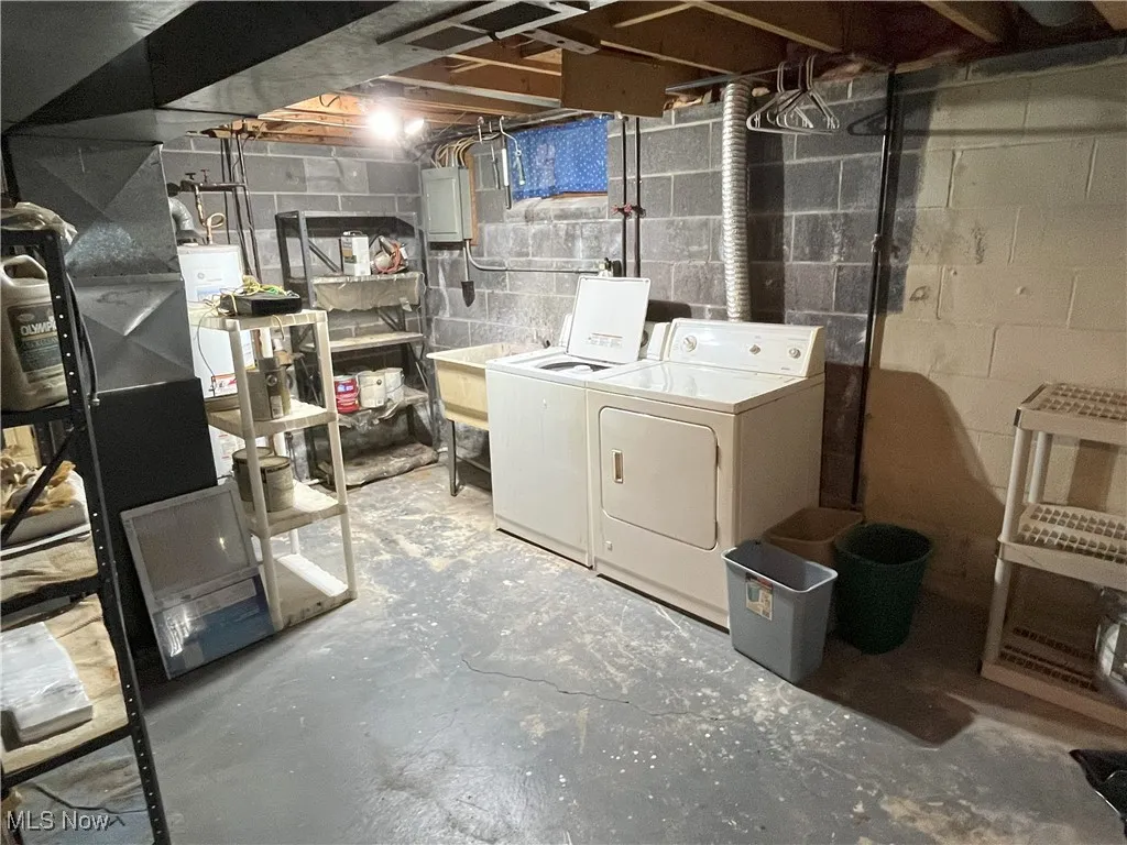 Unfinished basement area with washer and clothes dryer, electric panel, hot water tank, and AC(new)/furnace