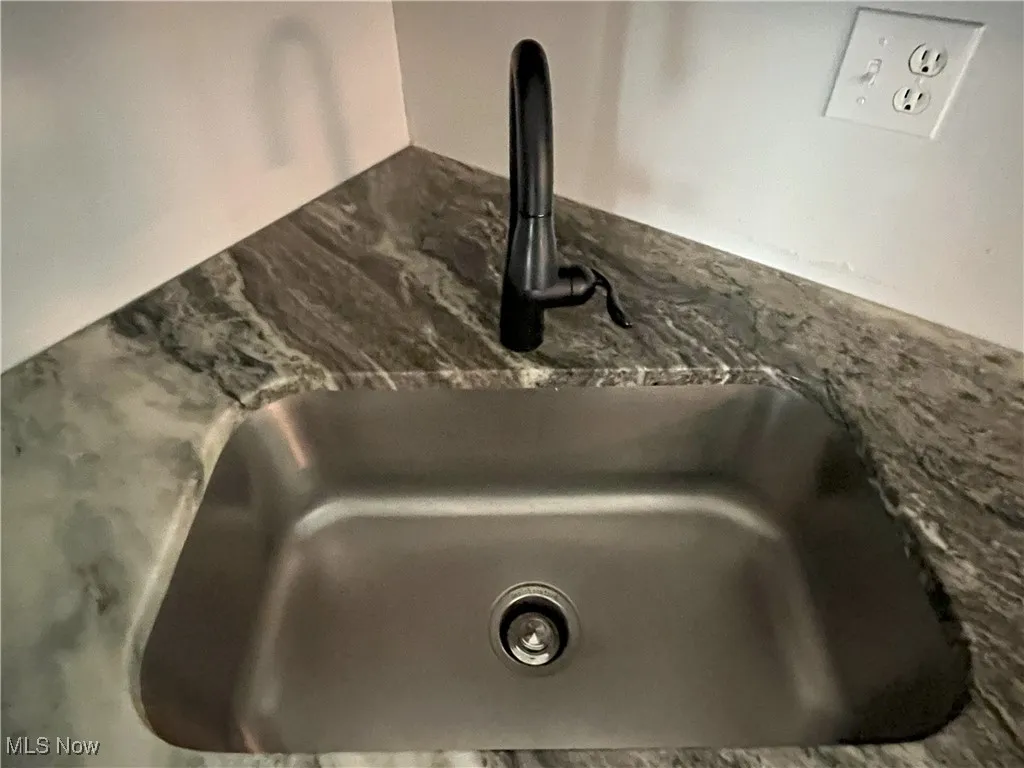 Kitchen view of stone countertops and deep sink.