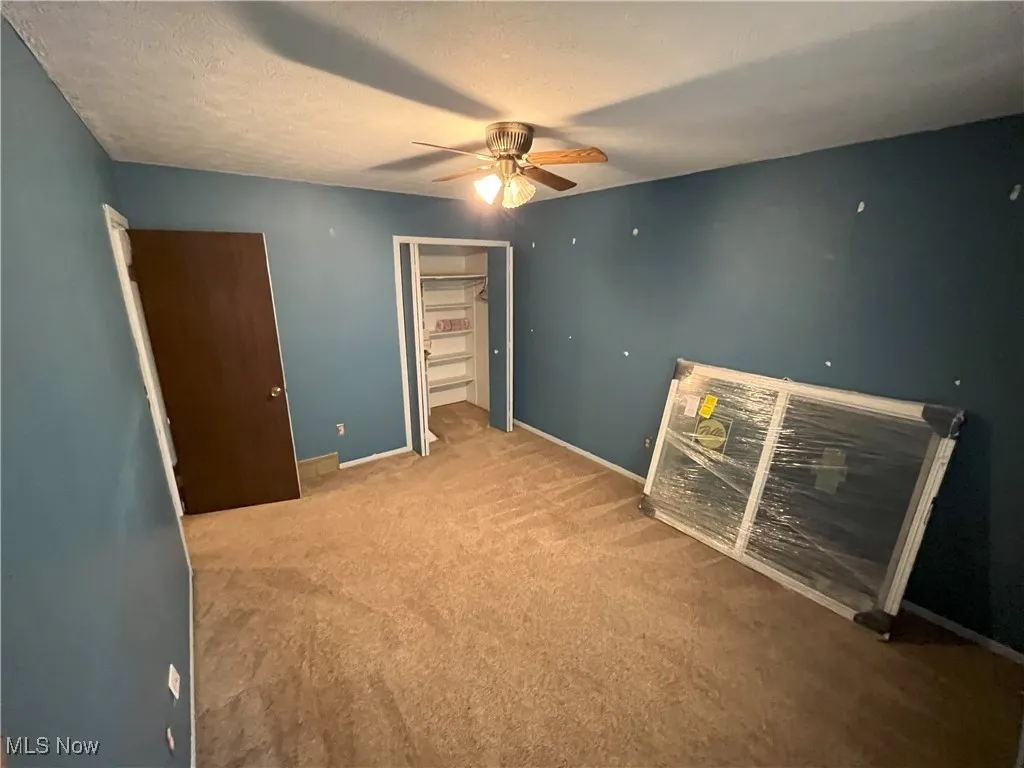 Bedroom with a ceiling fan, carpet floors, and new window to be installed.