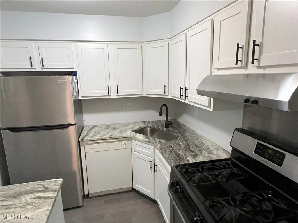 Kitchen view of newer white cabinets, granite counters including granite island, new light fixtures, stainless steel refrigerator/stove, dishwasher, and new lvt flooring.