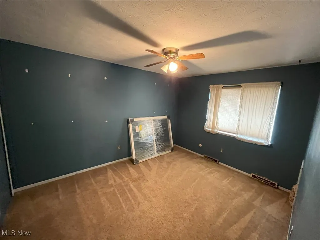 Bedroom with a ceiling fan, carpet floors, and new window to be installed.