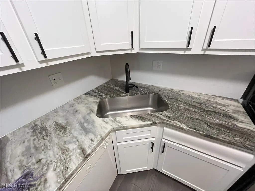 Kitchen view of newer white cabinets, granite counters, and dishwasher.
