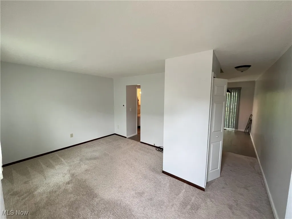 Unfurnished room featuring light colored carpet, ceiling fan, and baseboards
