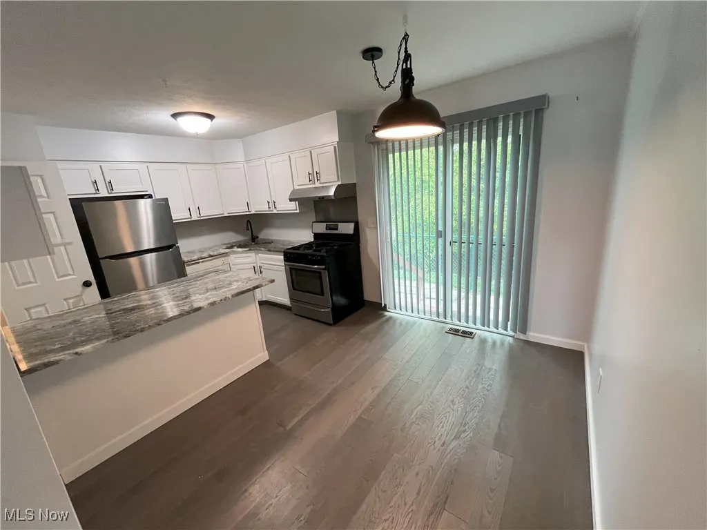 Kitchen view of newer white cabinets, granite counters, new light fixtures, and dishwasher.