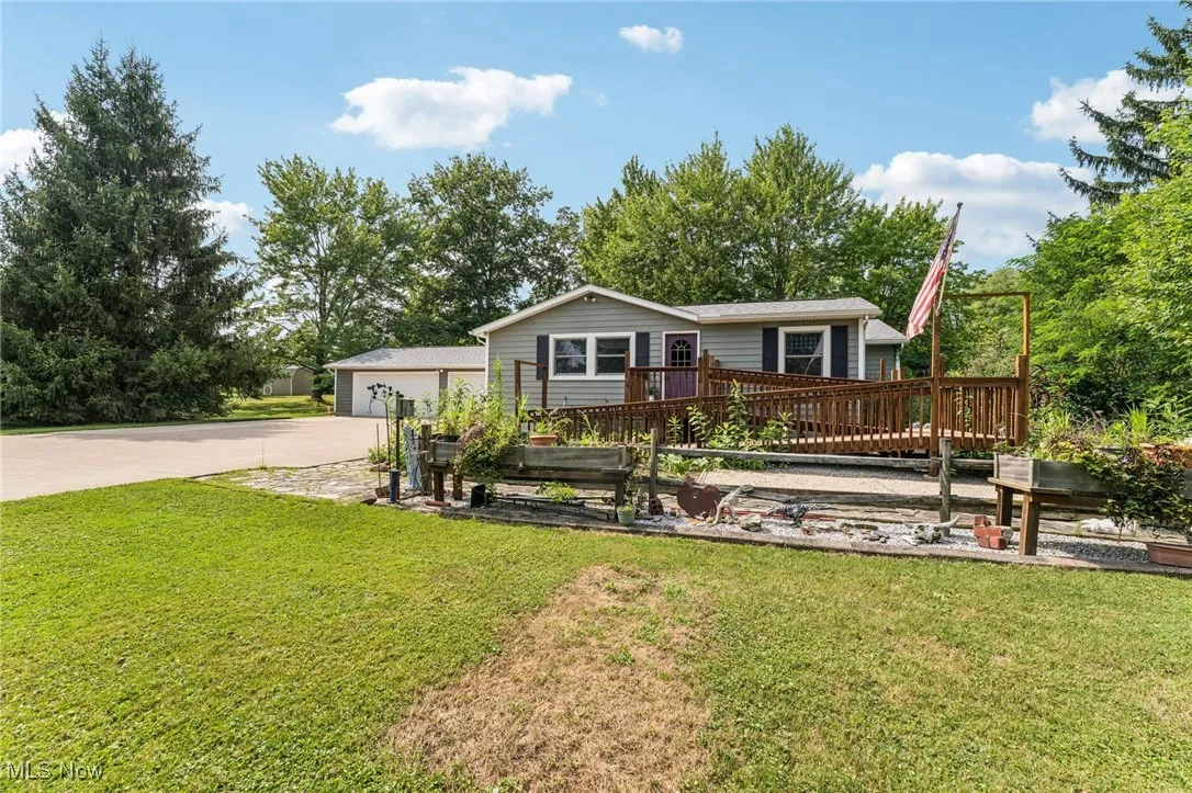View of front of property with driveway, a front yard, and a wooden deck