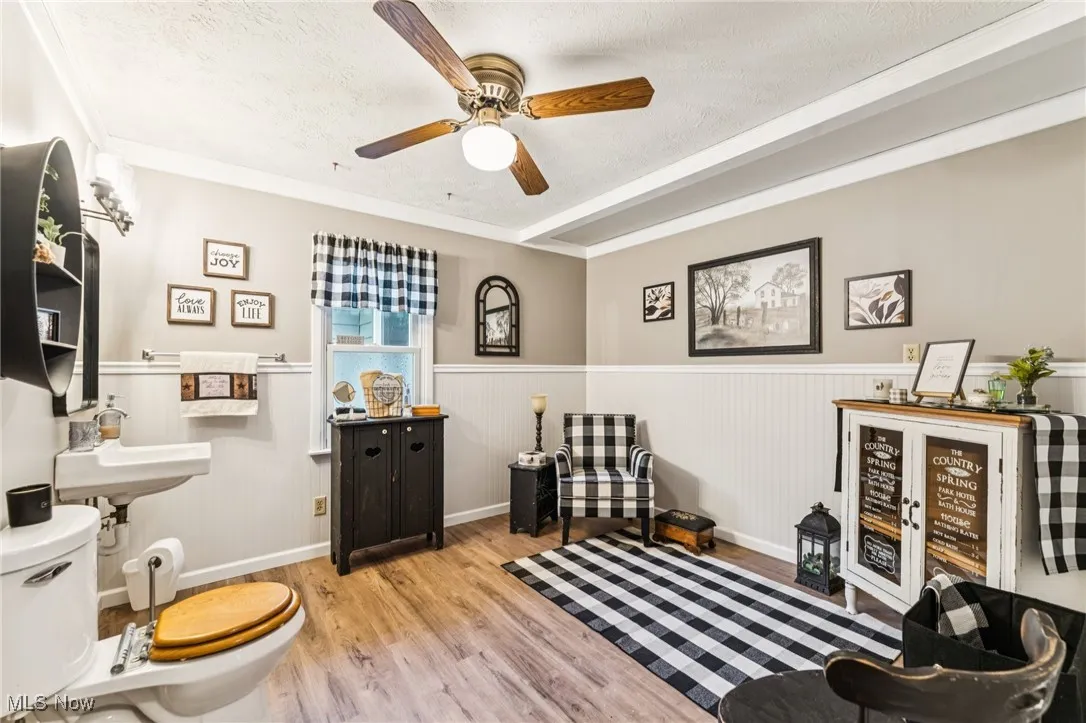 Bathroom with a wainscoted wall, a textured ceiling, wood finished floors, and ceiling fan