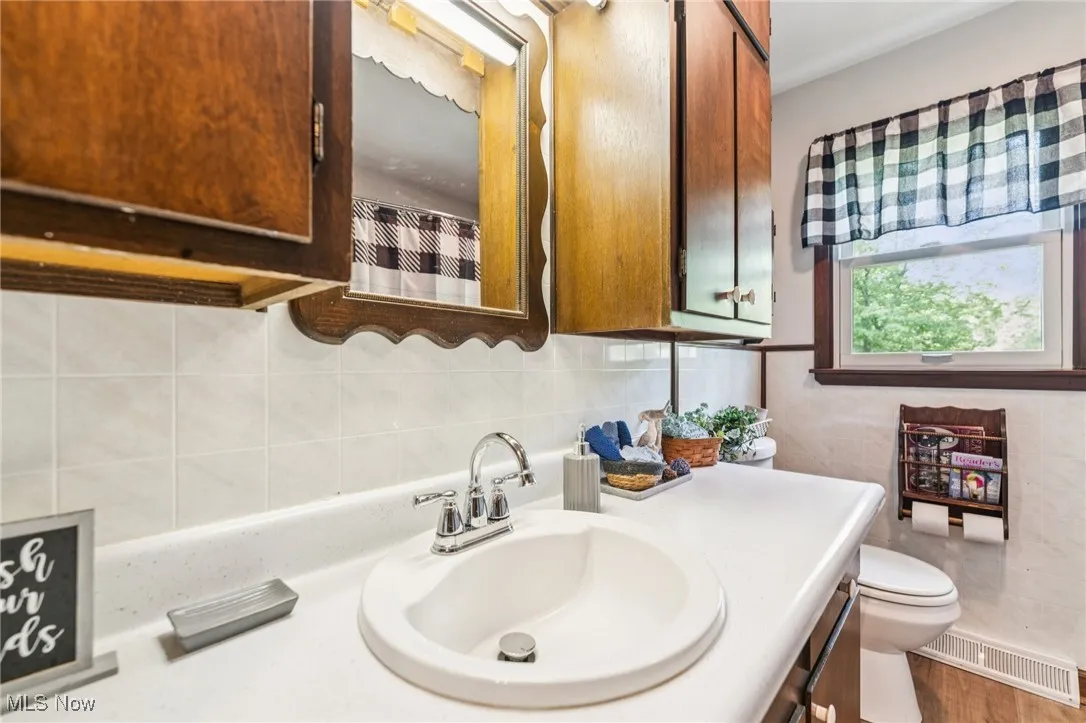 Bathroom with vanity, wood finished floors, and tile walls