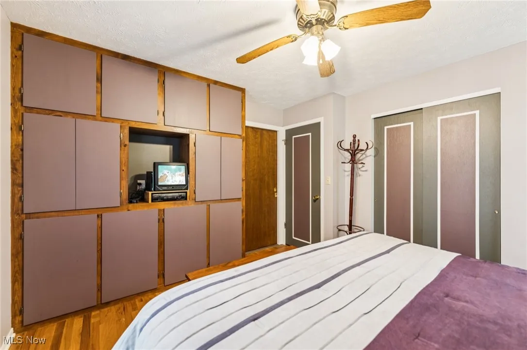 Bedroom with light wood-style floors, a textured ceiling, ceiling fan, and a closet