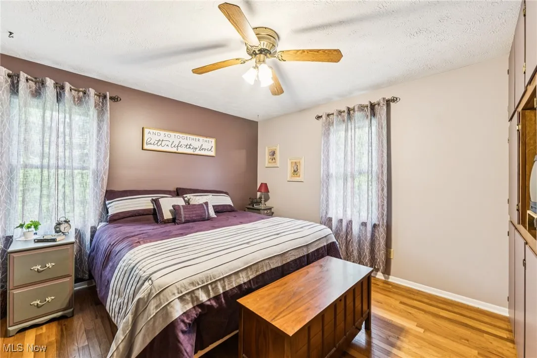 Bedroom with wood-type flooring, a textured ceiling, and ceiling fan