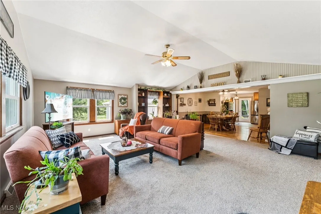 Living room with carpet flooring, vaulted ceiling, and a ceiling fan