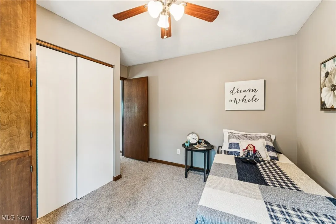 Bedroom with light colored carpet, ceiling fan, and a closet