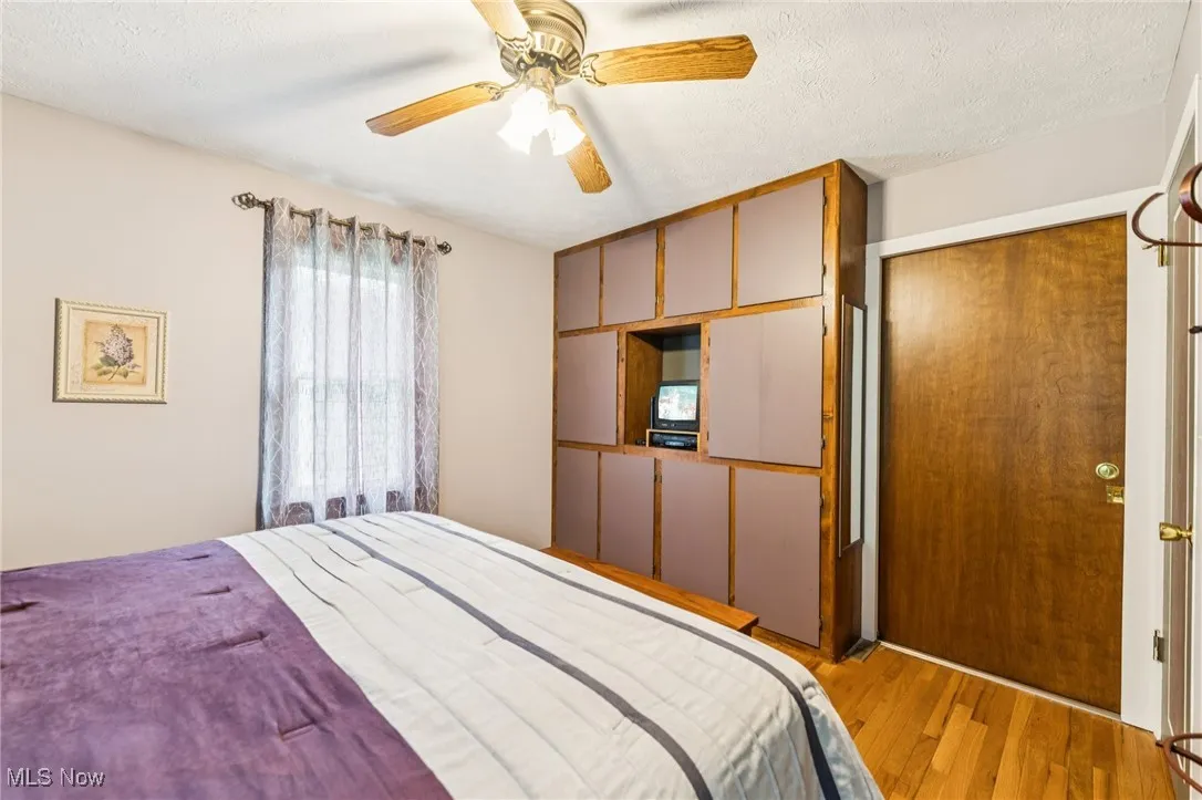 Bedroom featuring wood finished floors, a textured ceiling, and a ceiling fan