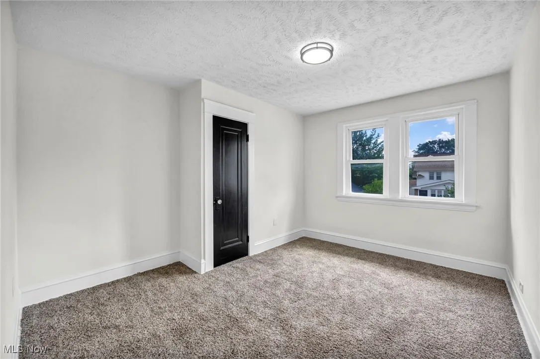 Carpeted spare room featuring a textured ceiling and baseboards