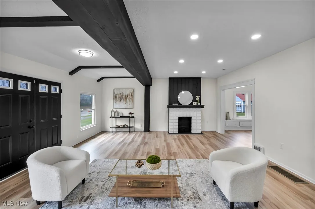 Living area with beamed ceiling, light wood-style floors, recessed lighting, and a fireplace