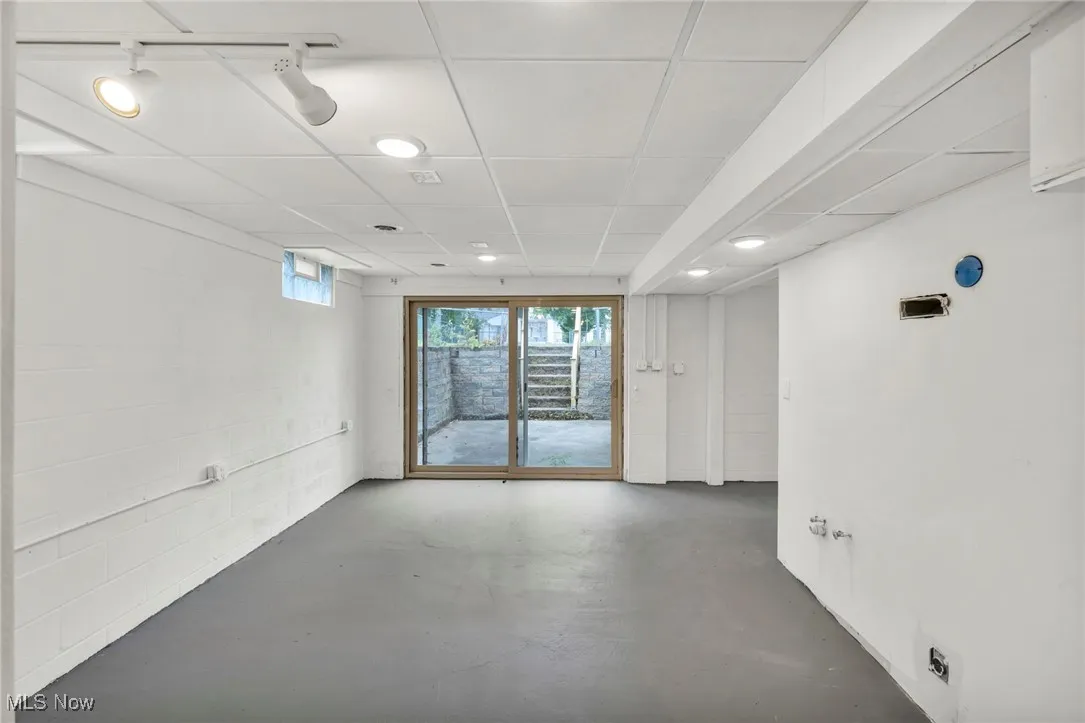 Spare room featuring concrete floors, a drop ceiling, and concrete block wall