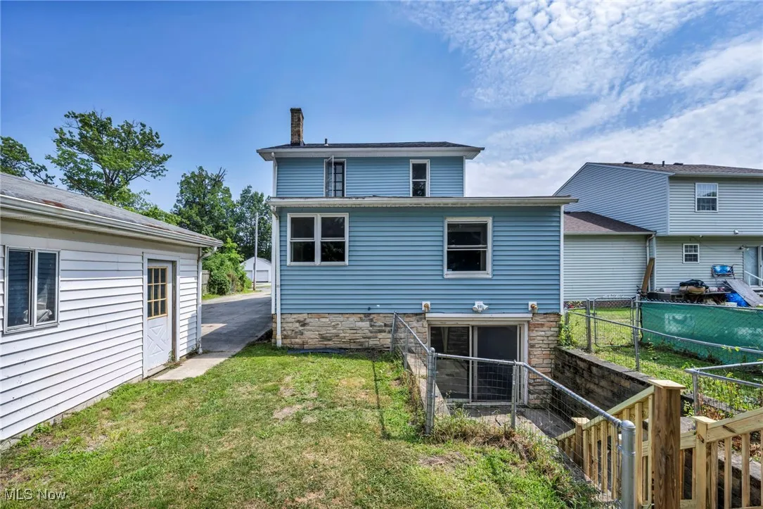 Rear view of property with a chimney and a yard