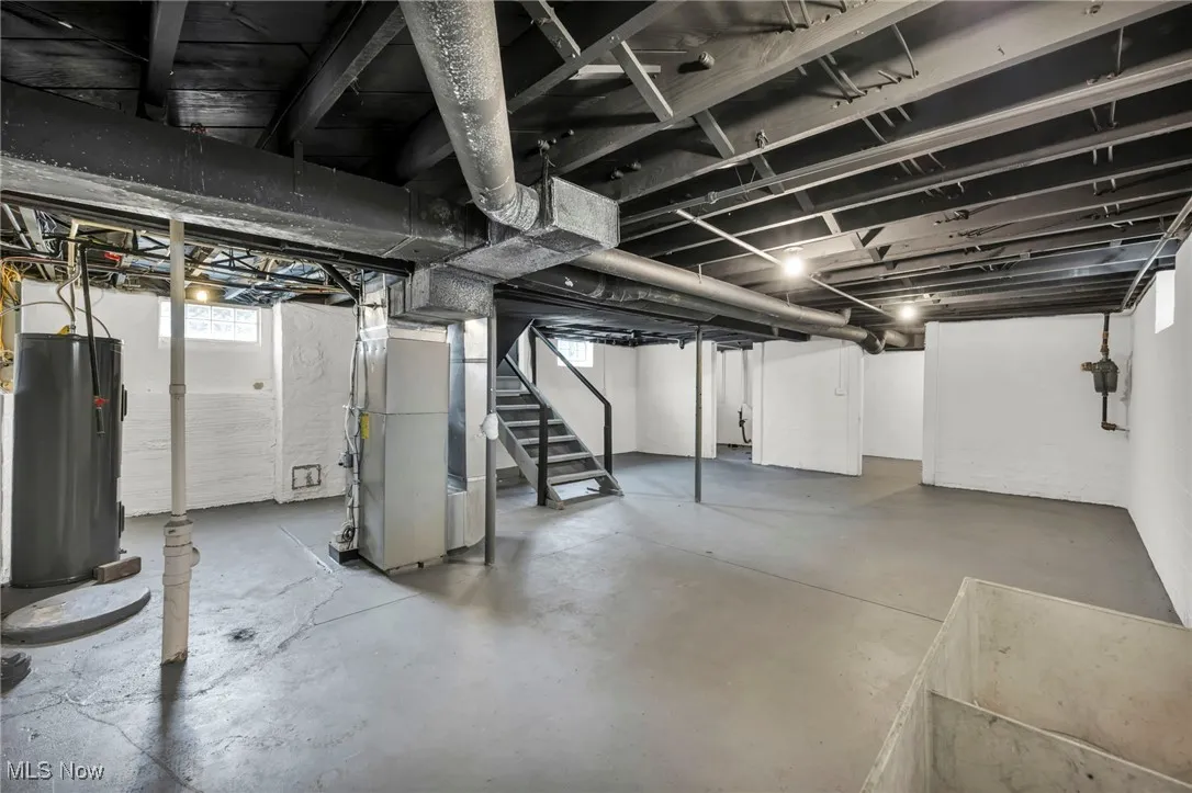 Basement featuring stairway, water heater, and heating unit