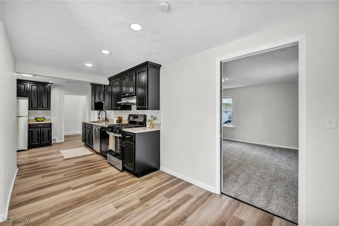 Kitchen featuring dark cabinets, appliances with stainless steel finishes, recessed lighting, light wood finished floors, and tasteful backsplash