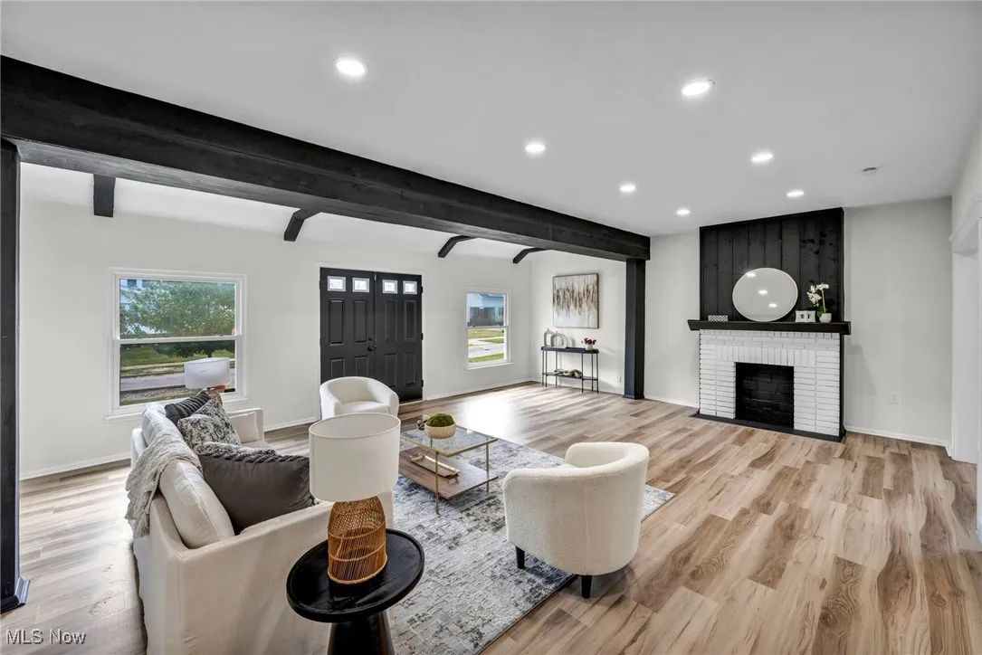 Living room with beamed ceiling, recessed lighting, light wood finished floors, and a fireplace