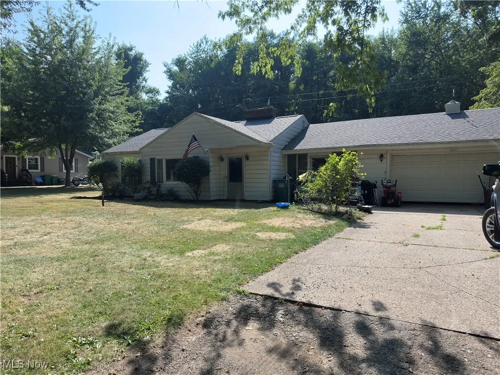 Single story home with a garage, concrete driveway, a front lawn, and roof with shingles