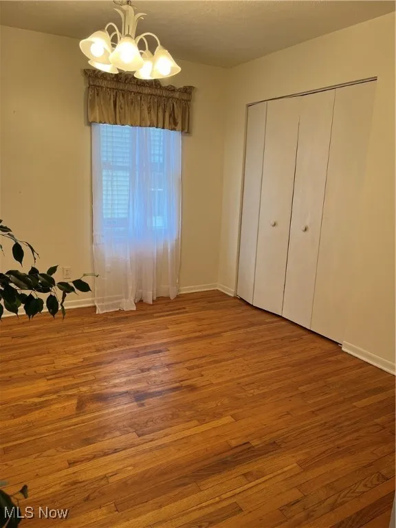 Unfurnished bedroom featuring hardwood / wood-style floors, a closet, a chandelier, and a textured ceiling