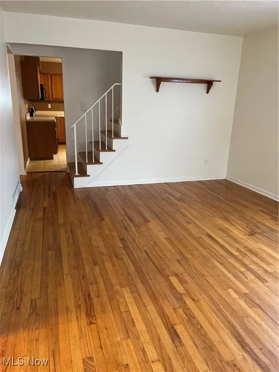 Unfurnished living room with dark wood finished floors and stairway