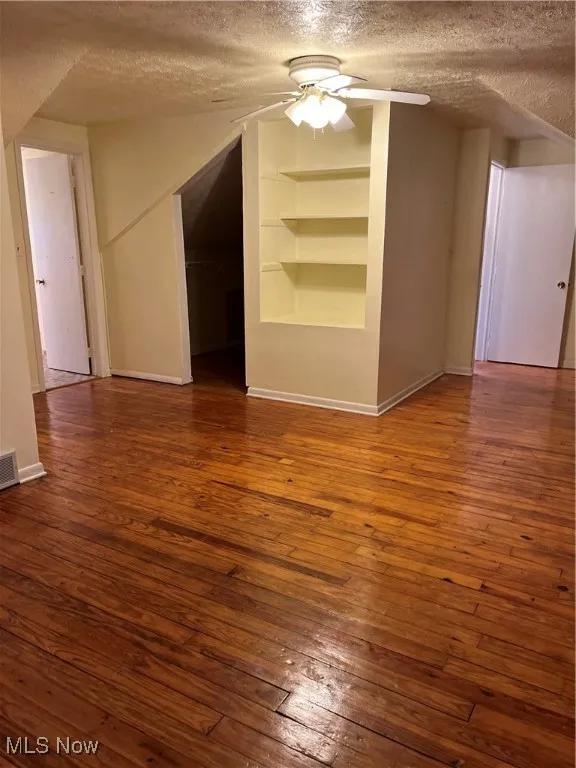 2nd floor master bedroom-featuring a textured ceiling, wood-type flooring, built in features, and ceiling fan