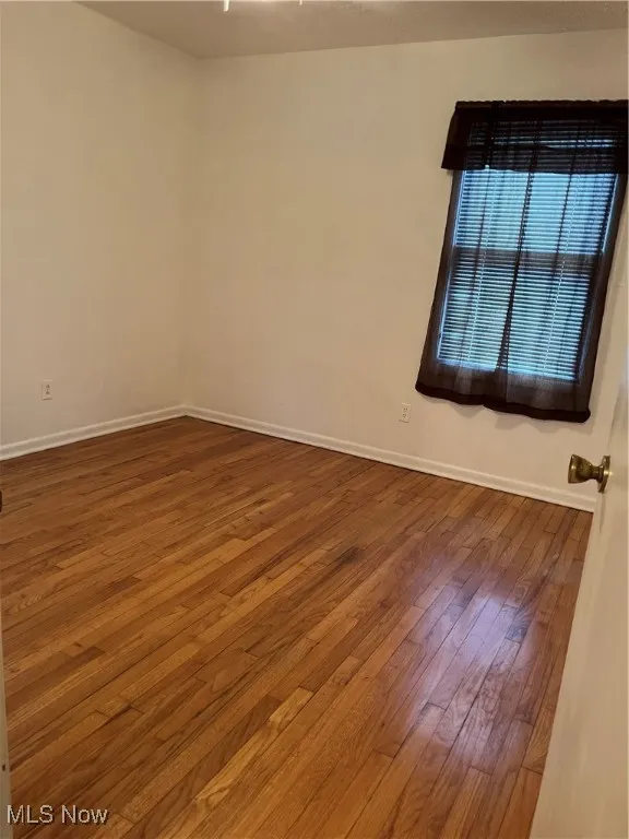 Spare room featuring dark wood-style floors and baseboards