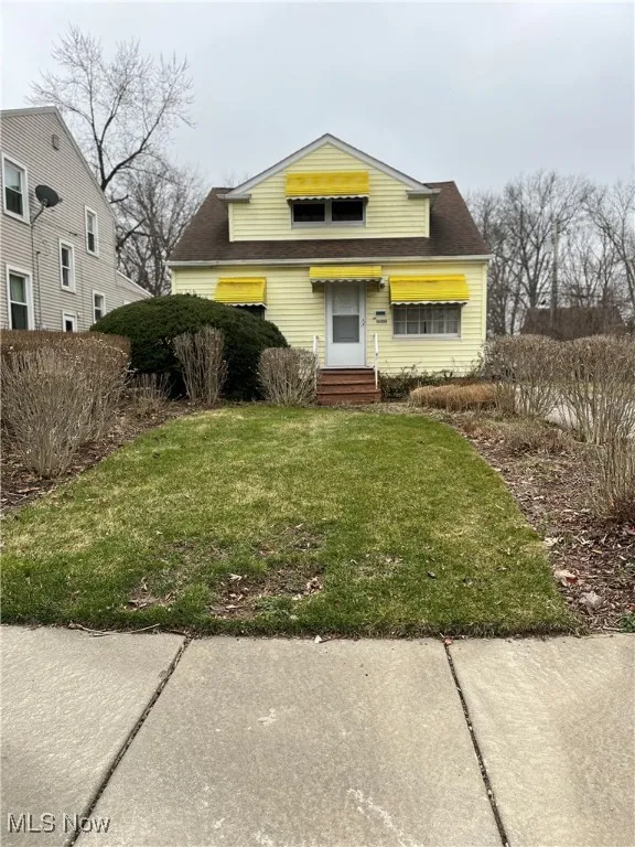 View of front of property with a front yard and a shingled roof