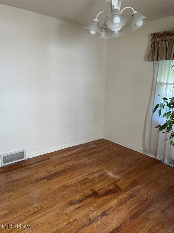Unfurnished bedroom featuring hardwood / wood-style floors, a closet, a chandelier, and a textured ceiling