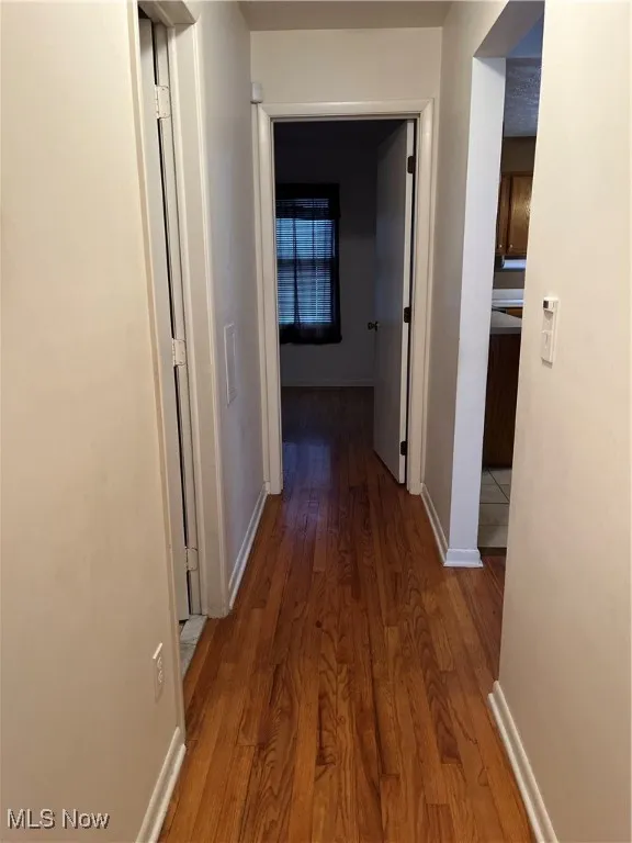 Hallway featuring dark wood finished floors and baseboards