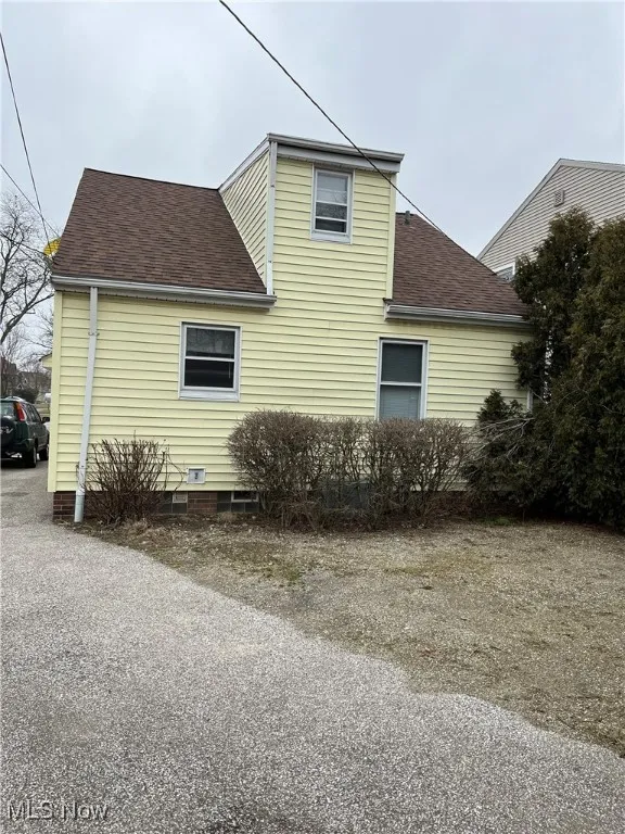 View of side of home with roof with shingles