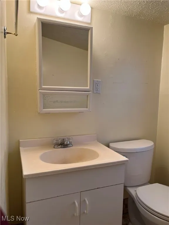 Half bath with vanity and a textured ceiling