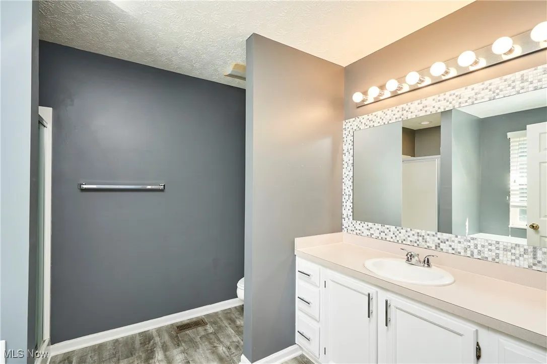 fPrimary Bathroom, a stall shower, a textured ceiling, and decorative backsplash
