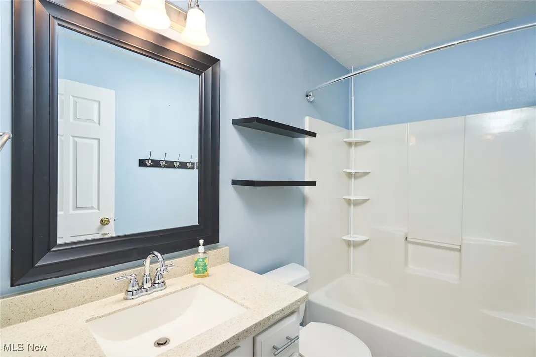 Bathroom featuring vanity, bathing tub / shower combination, and a textured ceiling