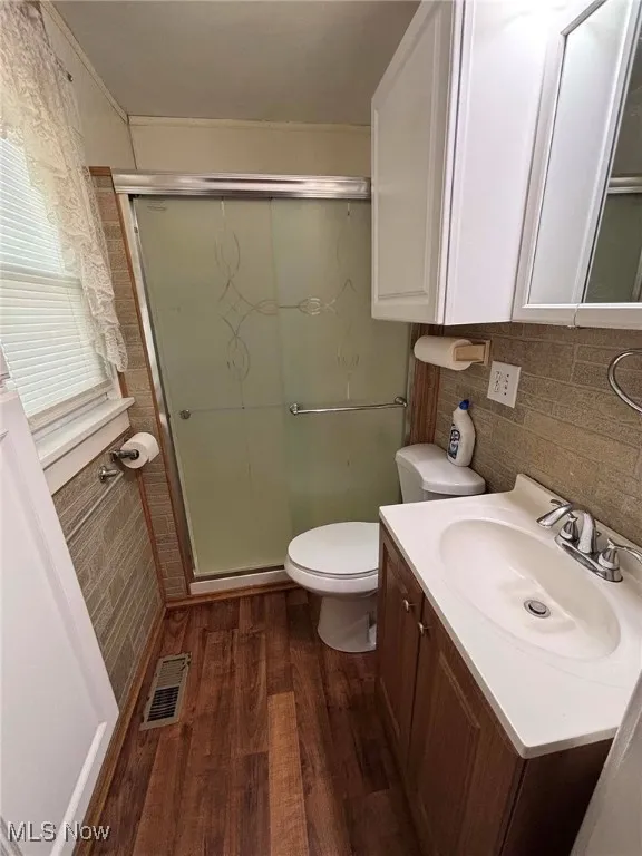 Full bathroom with dark wood-type flooring, vanity, and a shower stall