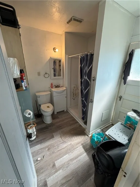 Full bath featuring a stall shower, wood finished floors, vanity, and a textured ceiling