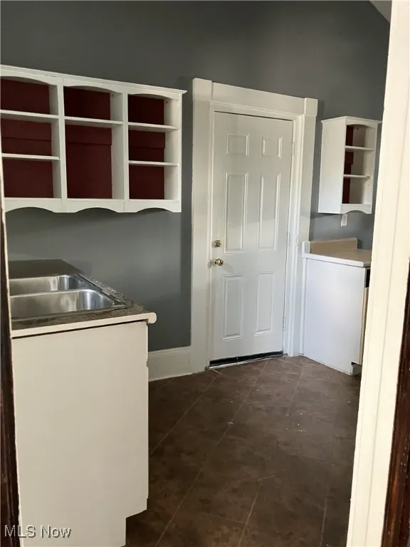 Kitchen with open shelves, white cabinetry, and dark tile patterned floors