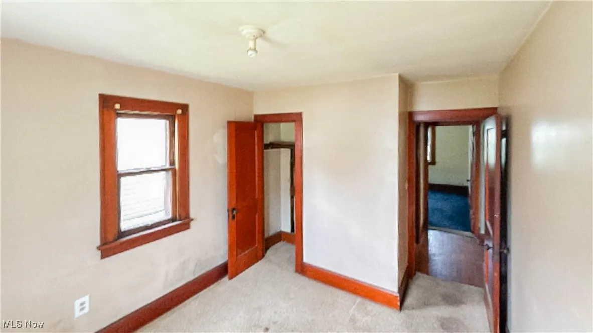 Unfurnished bedroom with light carpet and baseboards