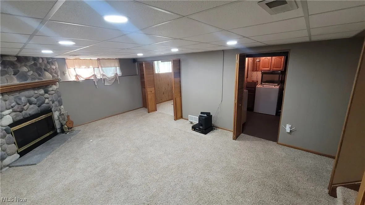 Basement with a drop ceiling, a fireplace, carpet floors, and recessed lighting