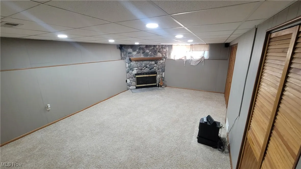 Below grade area featuring a paneled ceiling, a fireplace, and carpet flooring